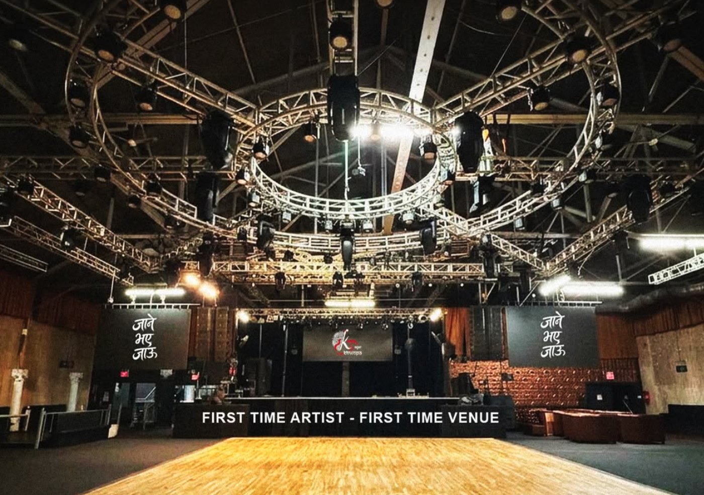 Inside Amazura Concert Hall — the main room, lighting truss and stage, with Kuma Sagar's artwork on the screens